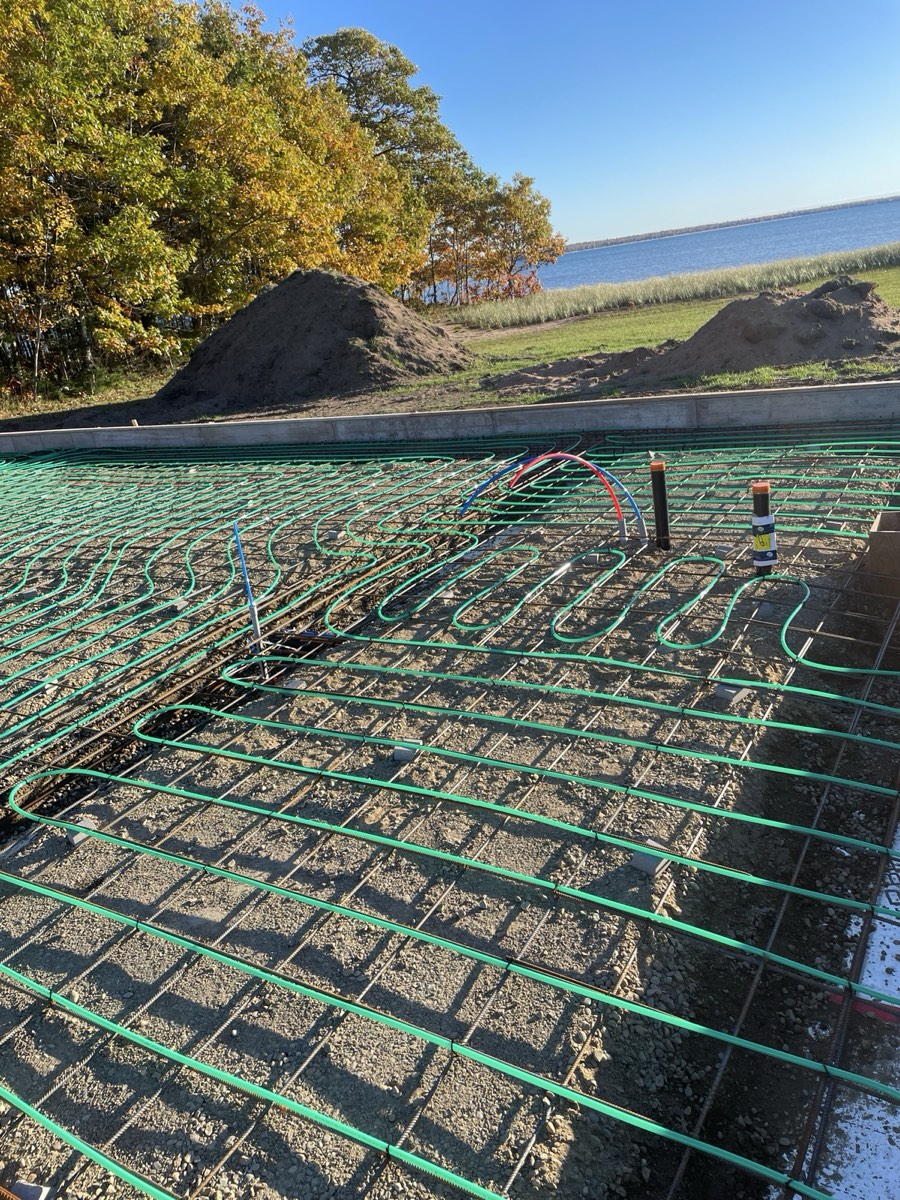 Radiant heat tubing and plumbing rough-in before concrete placement